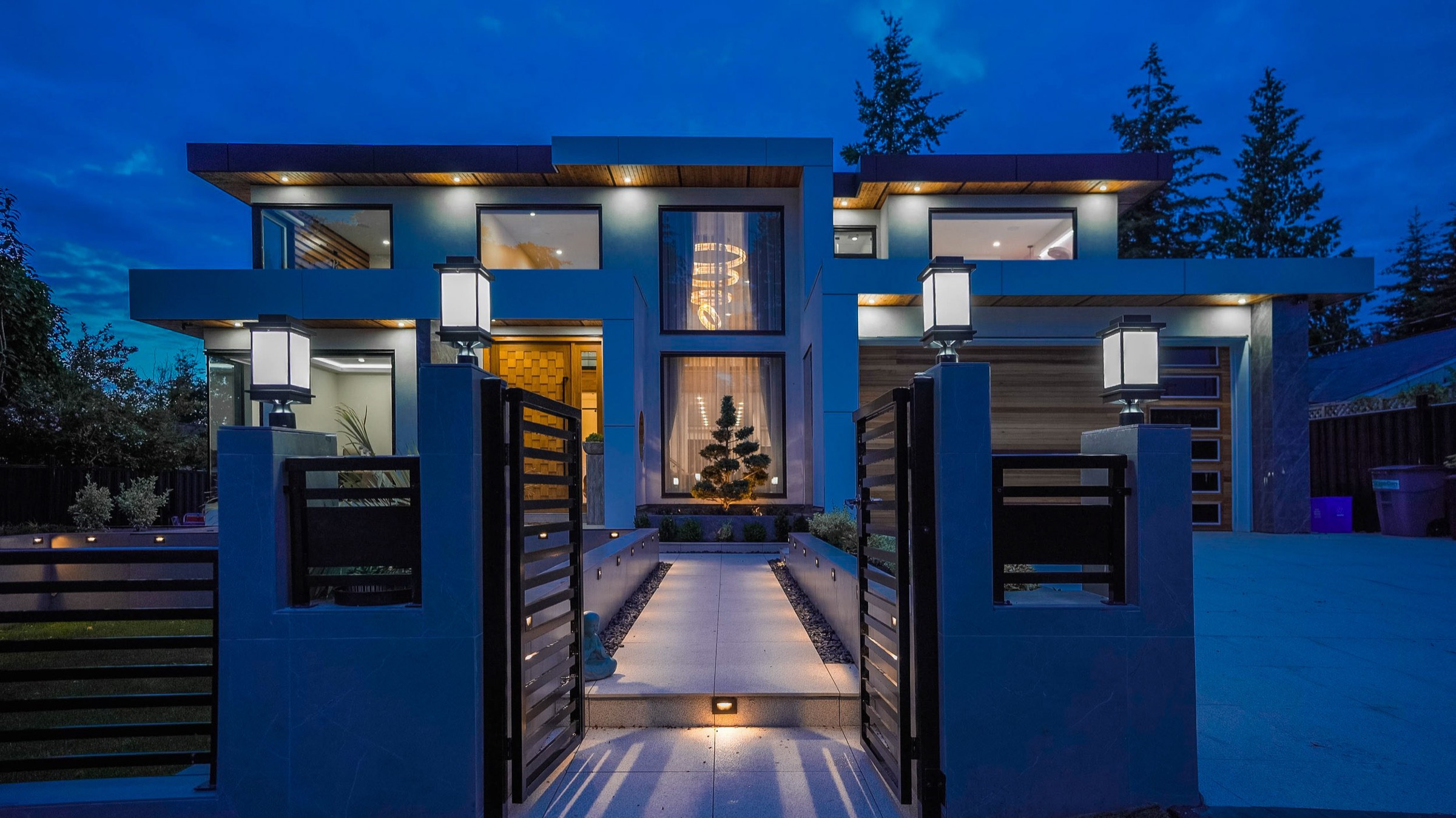 Completed custom home lit at dusk, with gated entry and cedar soffits