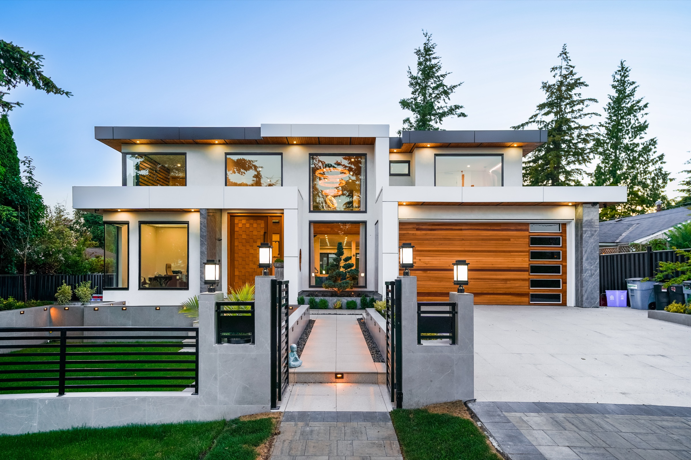 Completed custom home at dusk, with cedar soffits, a double garage and a lit entry path