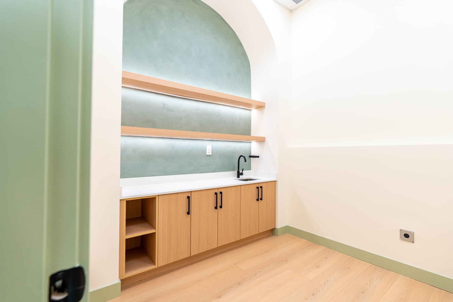 Clinic prep alcove with sink, cabinetry and open shelving